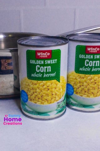 two cans of sweet corn and part of a saucepan.