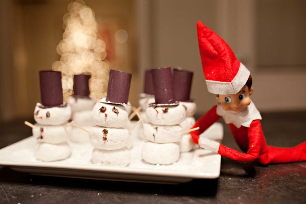 Christmas Elf laying by donut snowmen.